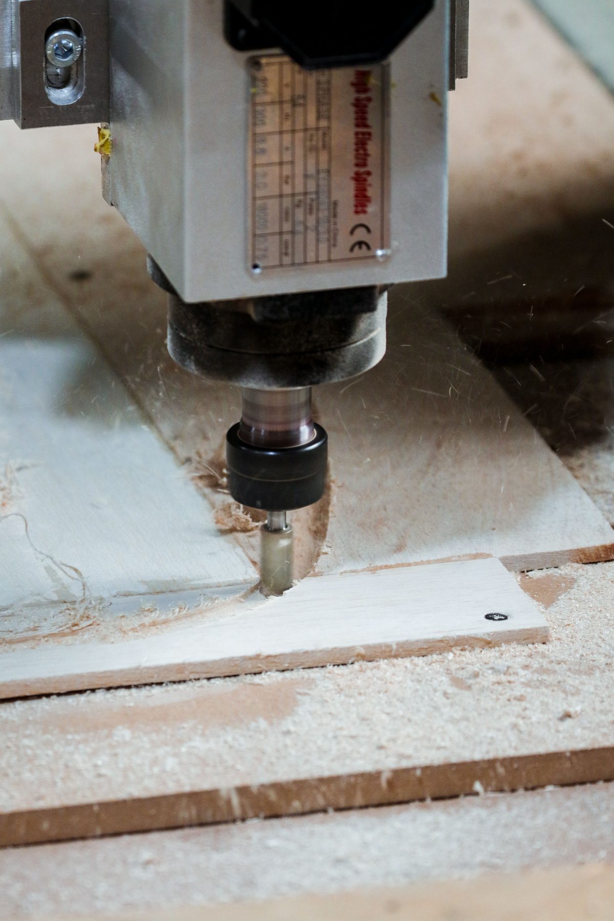 CNC spindle and router bit cutting a timber panel